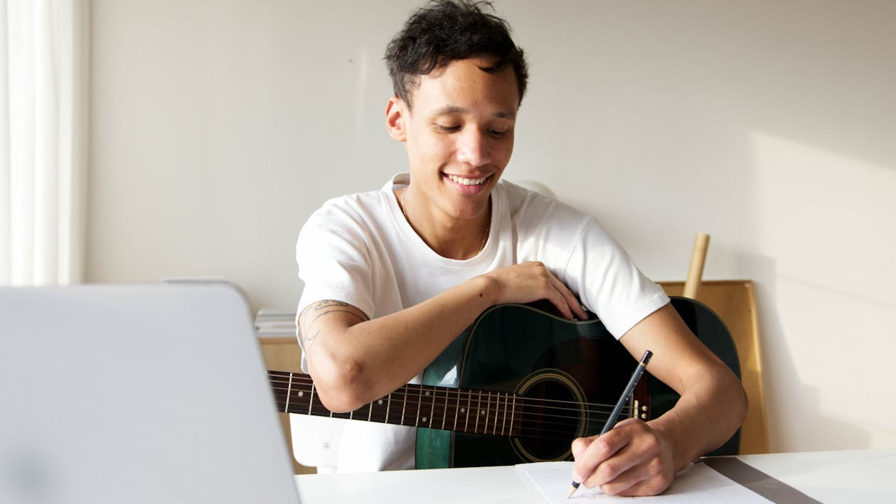Man learning a new skill using free resources while practicing guitar at home.