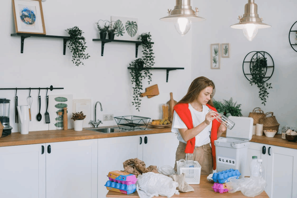 Woman sorting glass bottles, food items, plastics, paper bags in a low-waste home kitchen