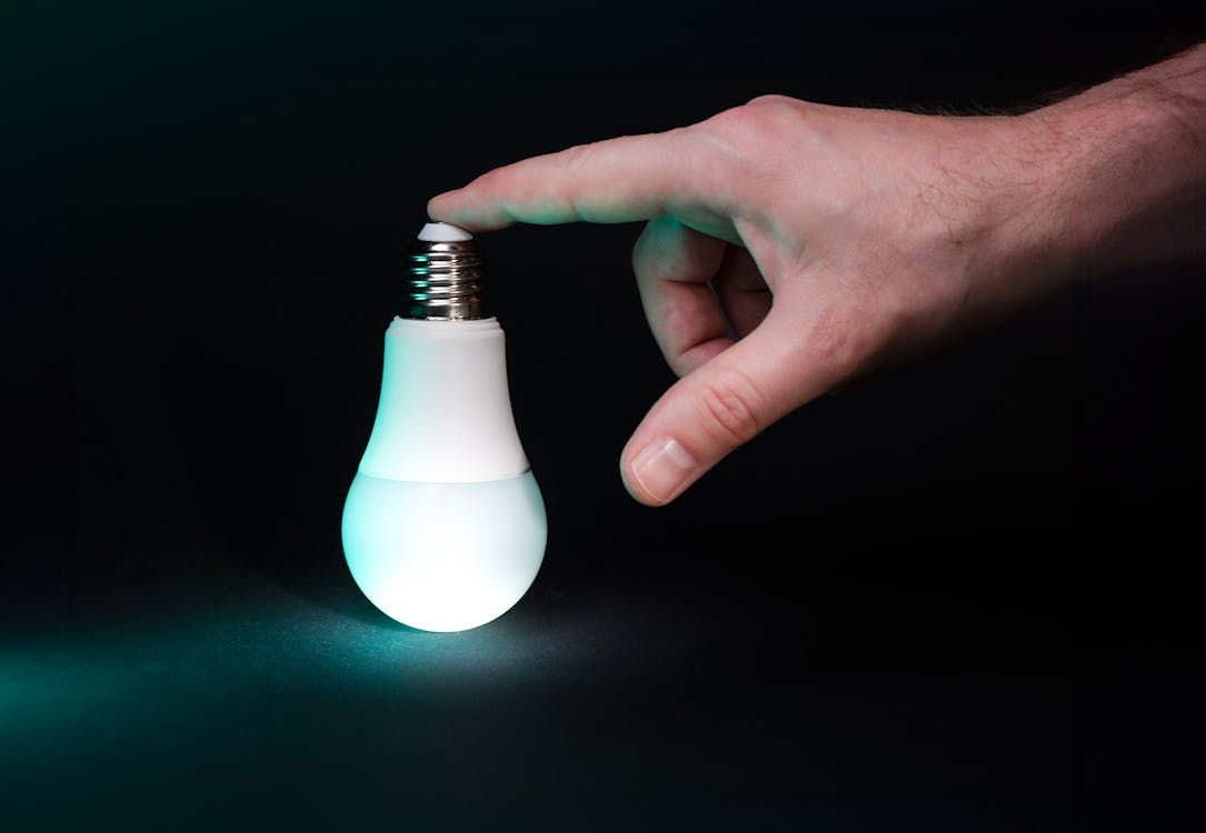 Hand holding an LED bulb as part of quick home energy-saving tips.