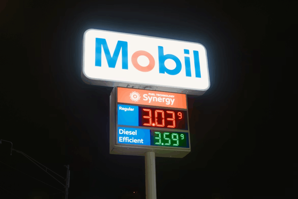 Gas station price sign at night showing fluctuating fuel costs.