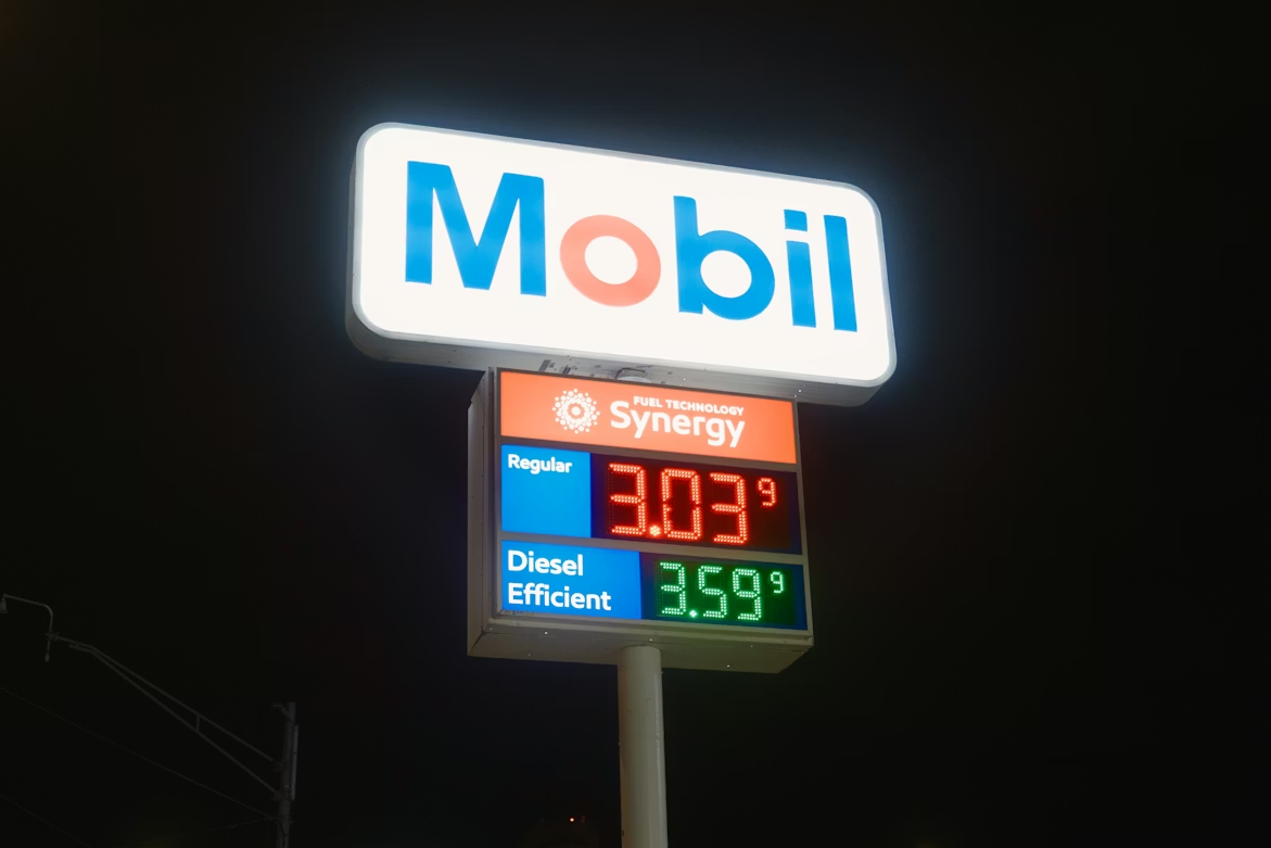 Gas station price sign at night showing fluctuating fuel costs.