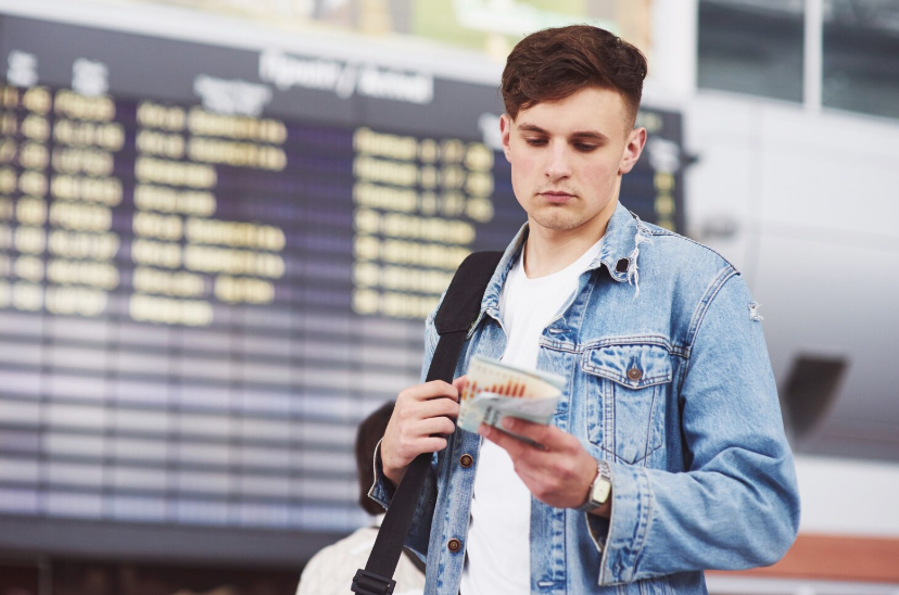 Traveler at airport checking tickets, illustrating beginner travel hacking tips.
